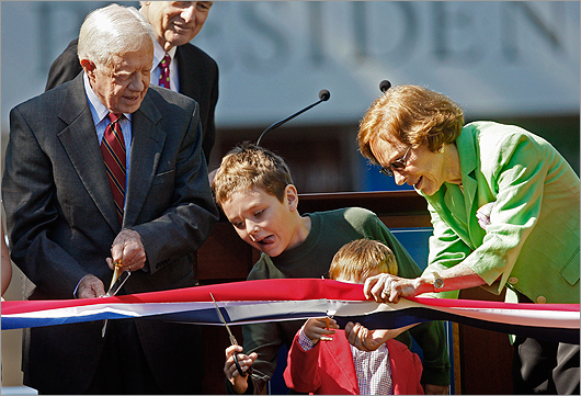 Former president Jimmy Carter looked on as his grandson Hugo Wentzel, and great-grandson Henry Carter, second from left, cut a ribbon with the help of Rosalynn Carter during the reopening ceremony for the newly designed Jimmy Carter Presidential Library and Museum on Thursday in Atlanta. Carter was also celebrating his 85th birthday.