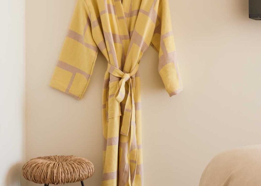 A colorful, yellow striped robe hangs next to a wooden stool