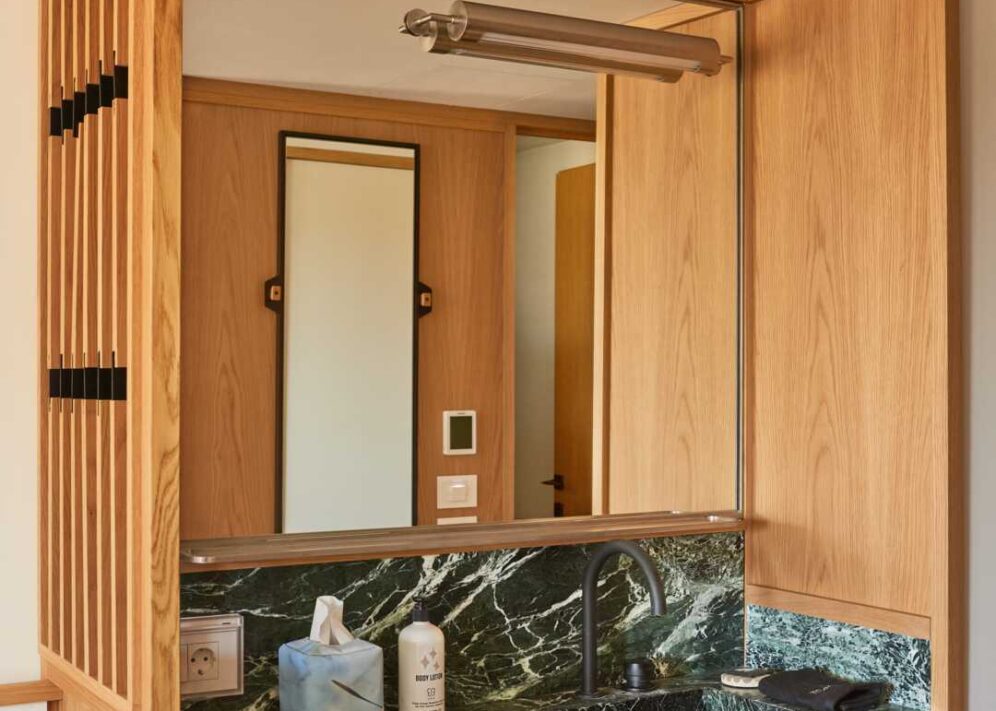 A bathroom with a large mirror and green limestone sink provide a space to prepare for the day