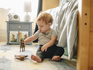 toddler on floor with toy horse and sheep