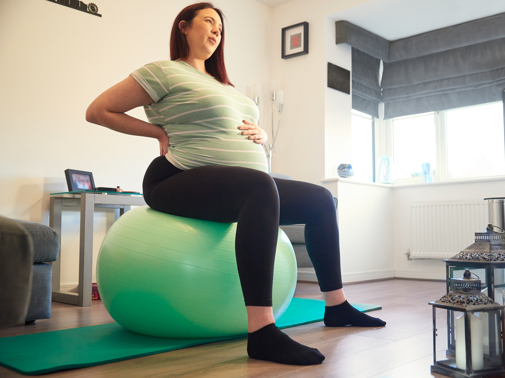 A pregnant woman sitting on an exercise ball 