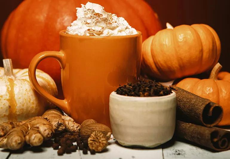 Pumpkin-spices in foreground with pumpkins and latte in background.