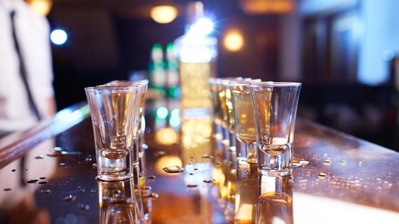 A double row of shot glasses lined up on a bar