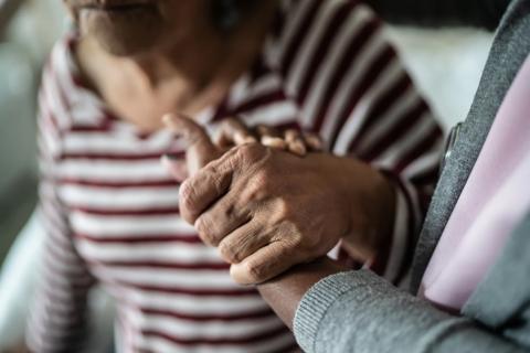 Elderly patient’s hand being held by a caregiver