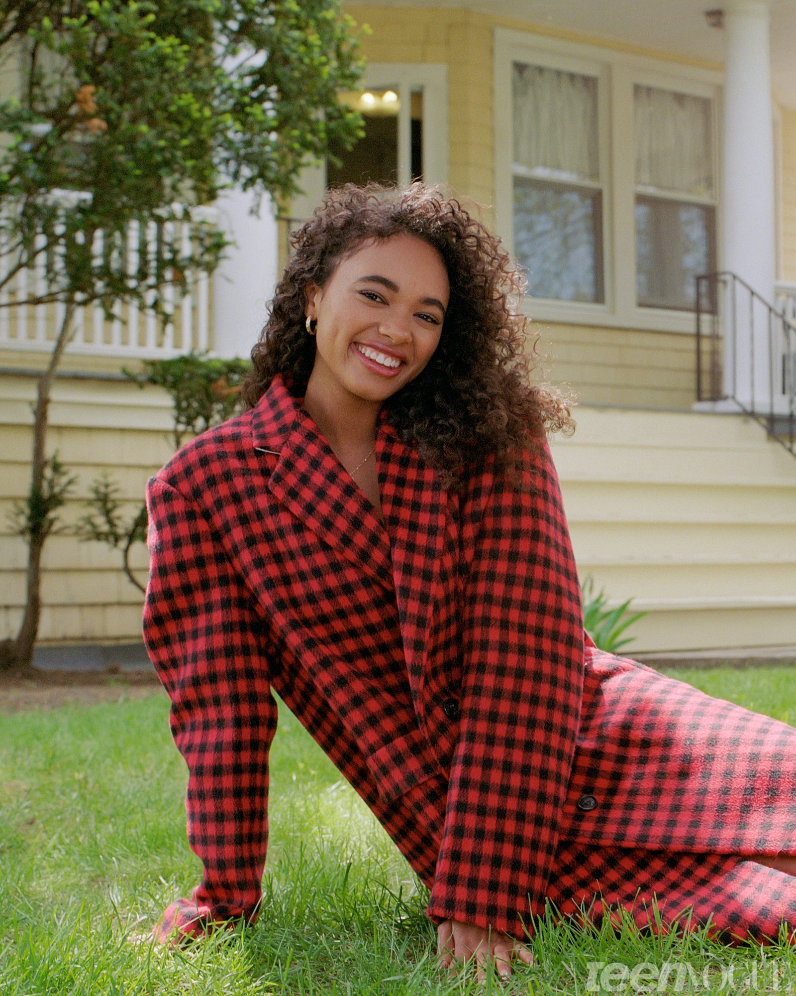 Chandler relaxed in the grass smiling in front of a house