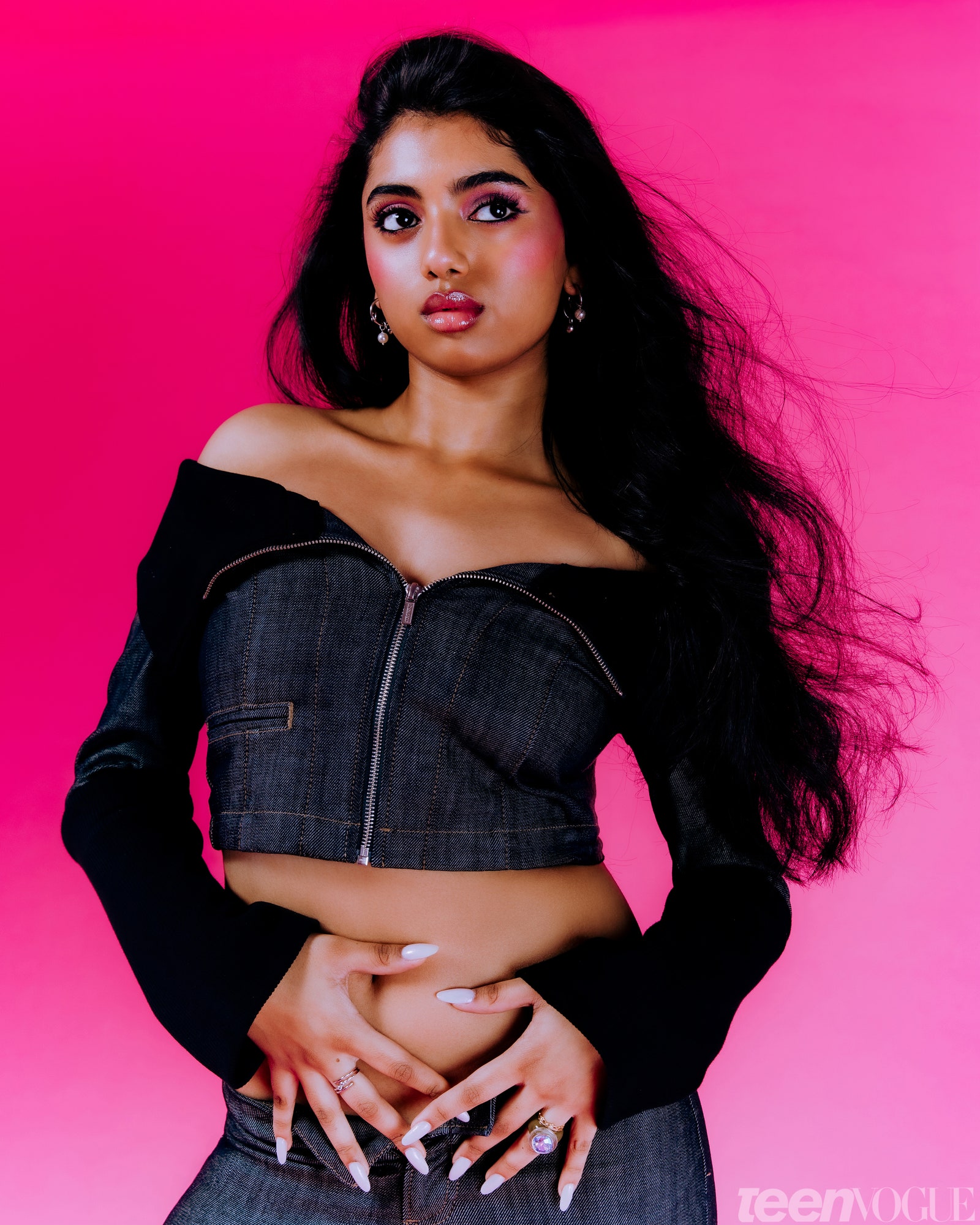 Avantika against a pink background with pink blush hands on hips