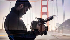 Two images are overlayed: a person recording with a video camera and a view of the golden gate bridge