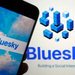 The app for Bluesky is shown on a mobile phone and on a laptop screen.