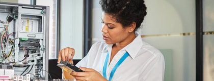 Female technician rerouting networking cables connected to an open service panel