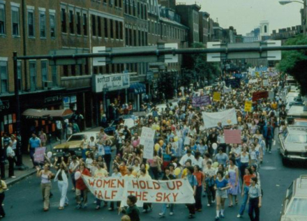 Community members in 1979 Boston's annual Pride march holding a sign that reads "Women Hold Up Half the Sky"