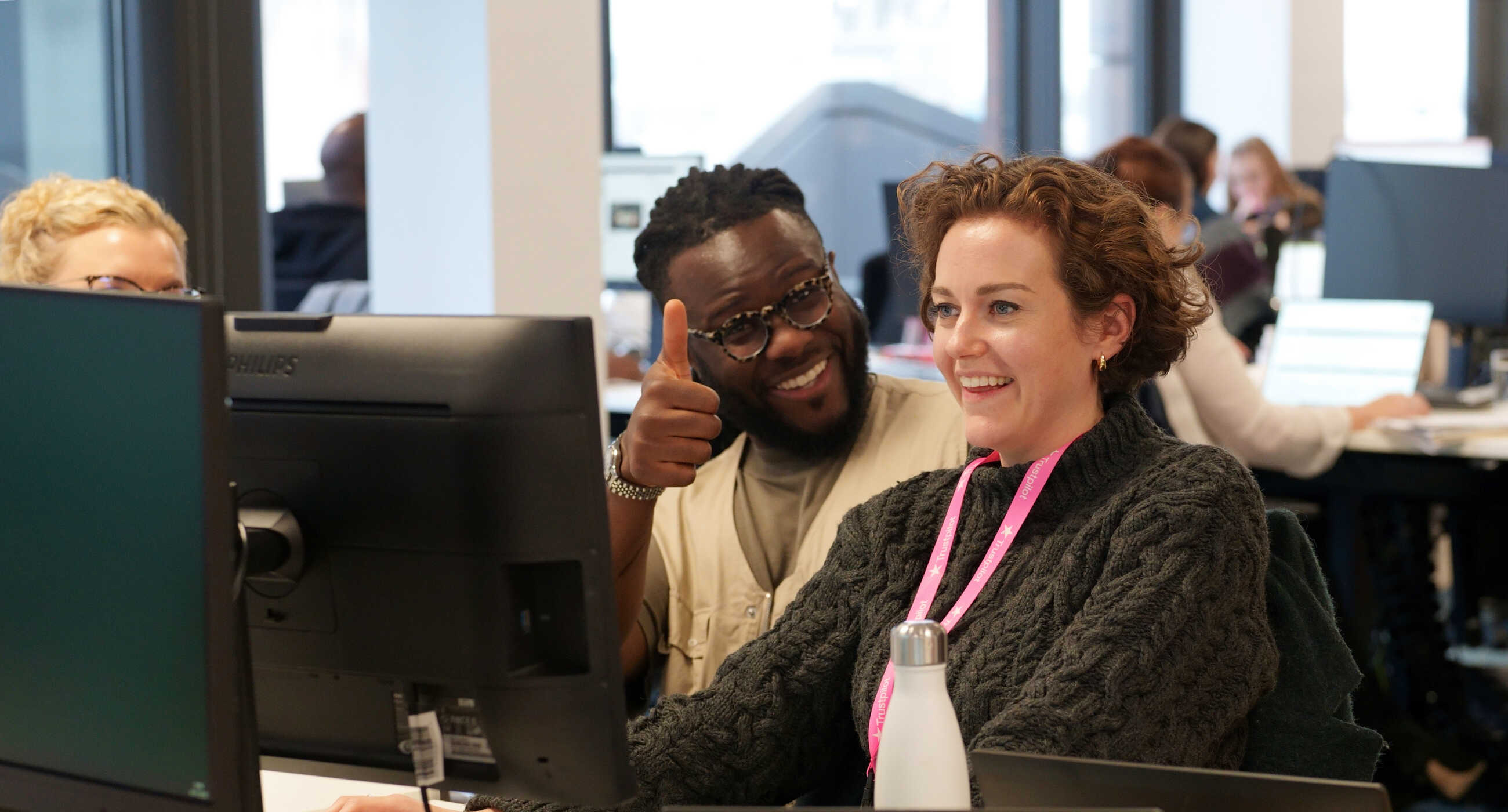 Une photographie de deux employés engagés dans une conversation dans les bureaux de Trustpilot.