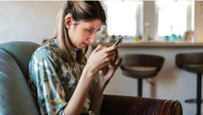 Blind young adult female with hearing aids using a smartphone.