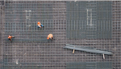 Aerial view of construction workers working on a steel grid foundation.