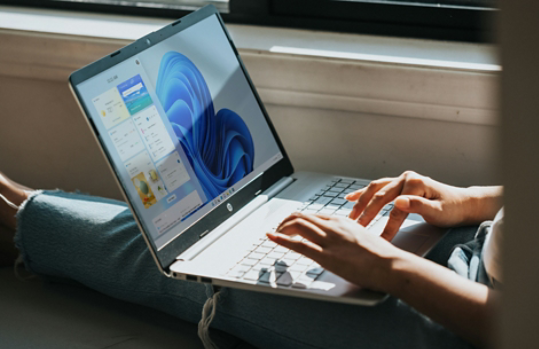 A person using a Windows 11 laptop on their lap