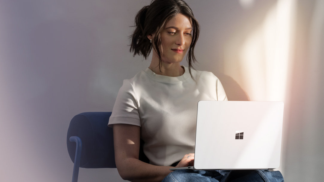 A woman using a Surface Laptop 7th Edition on her lap