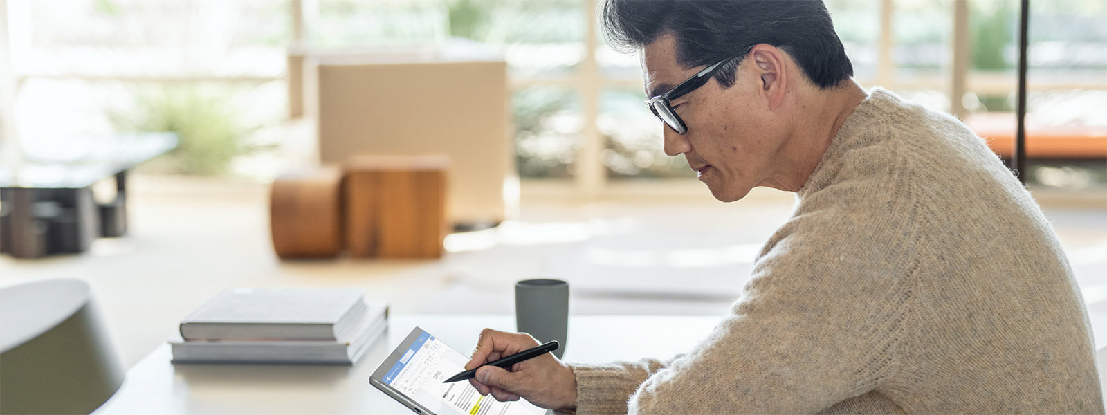 Man zit aan een tafel en gebruikt een Surface Pen op zijn Surface-apparaat