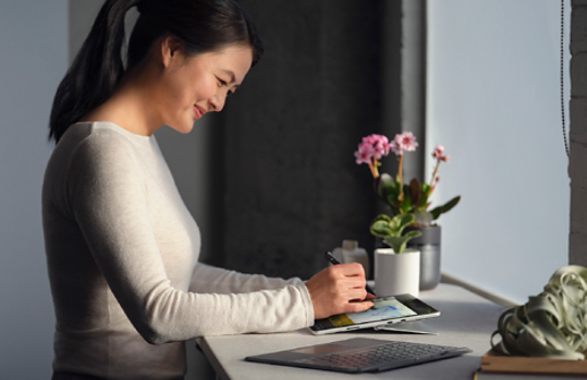 Woman using a digital pen on her Surface device on an island counter