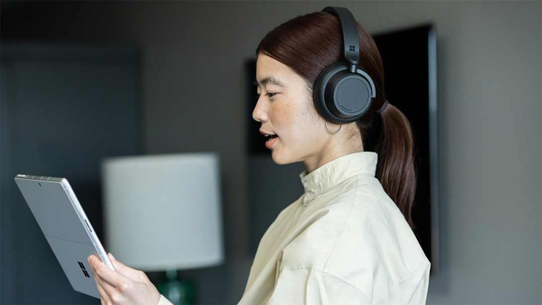 Vrouw met koptelefoon en Surface-apparaat tijdens een videogesprek