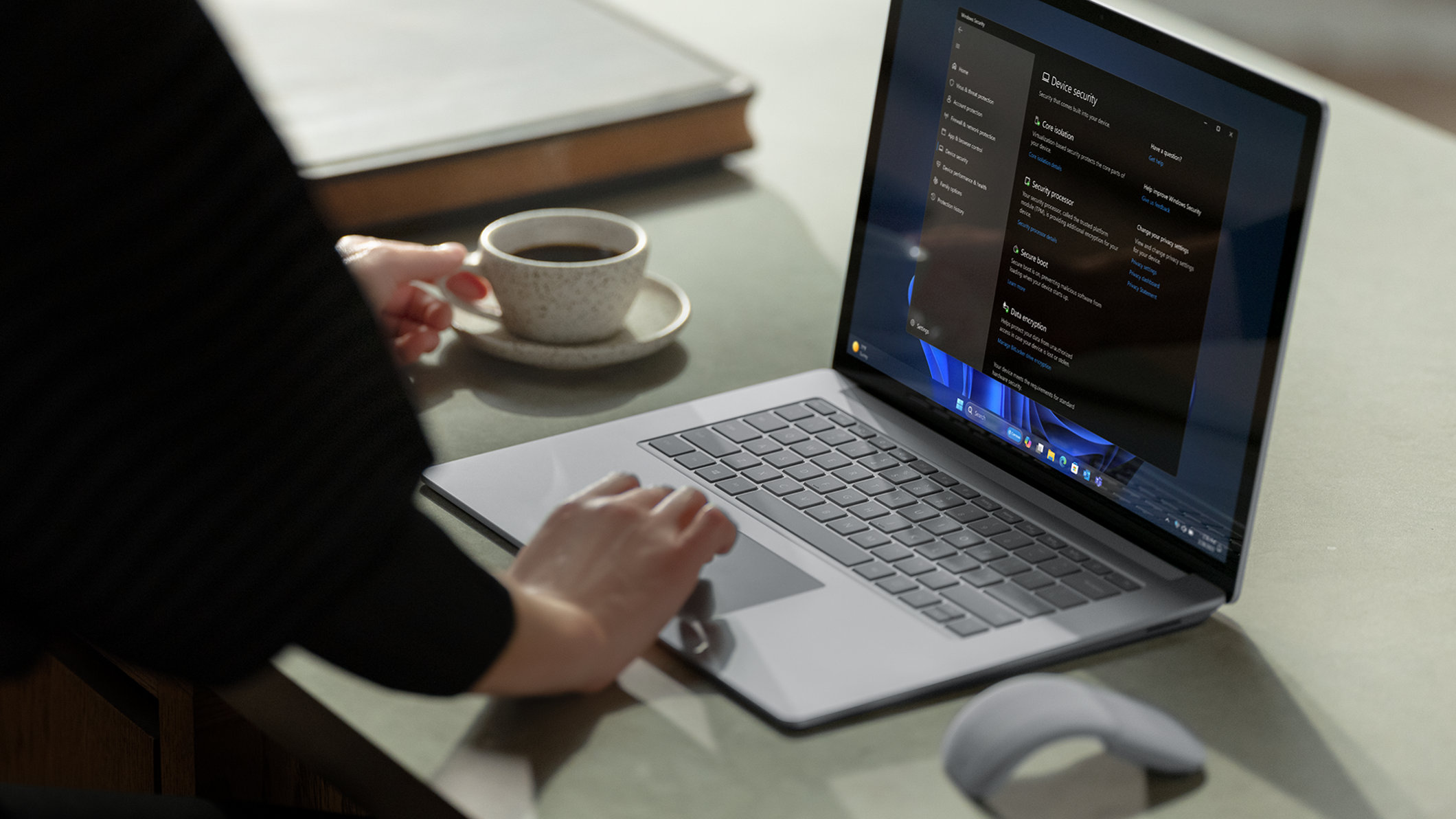 Woman working at desk on laptop with coffee in other hand