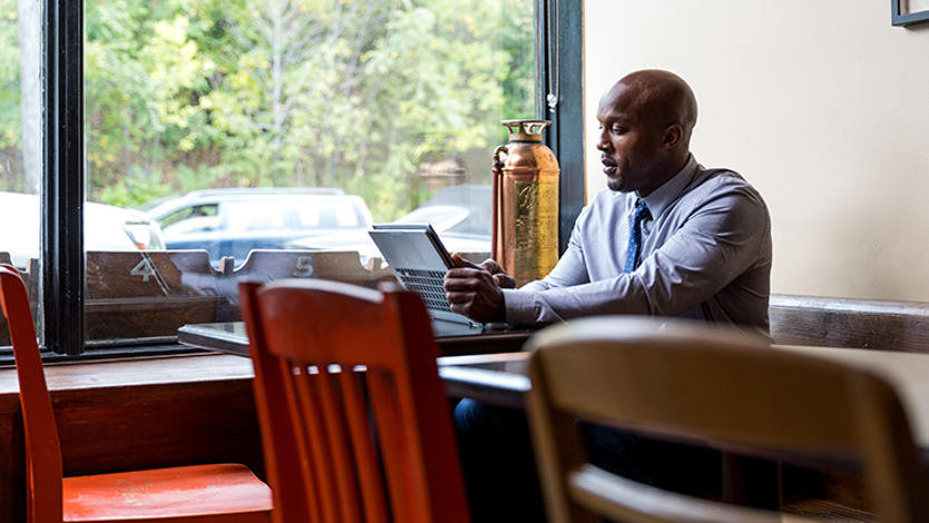 Remote business professional sitting in café using a convertible laptop as a tablet.