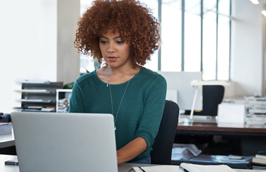 A female designer sitting at a desk using a Surface laptop.