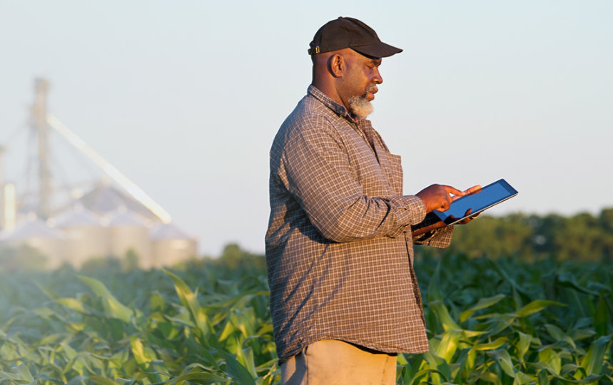 Farmer holding a digital tablet in a crop field.