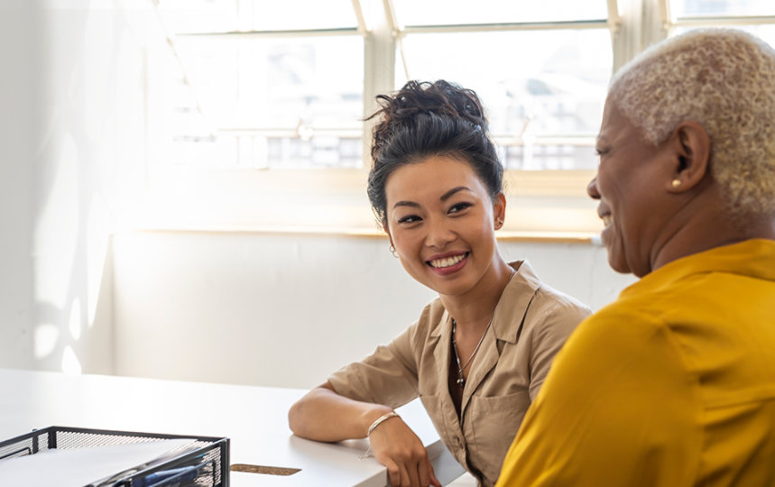 Businesswomen sitting in an office at a table and talking. 