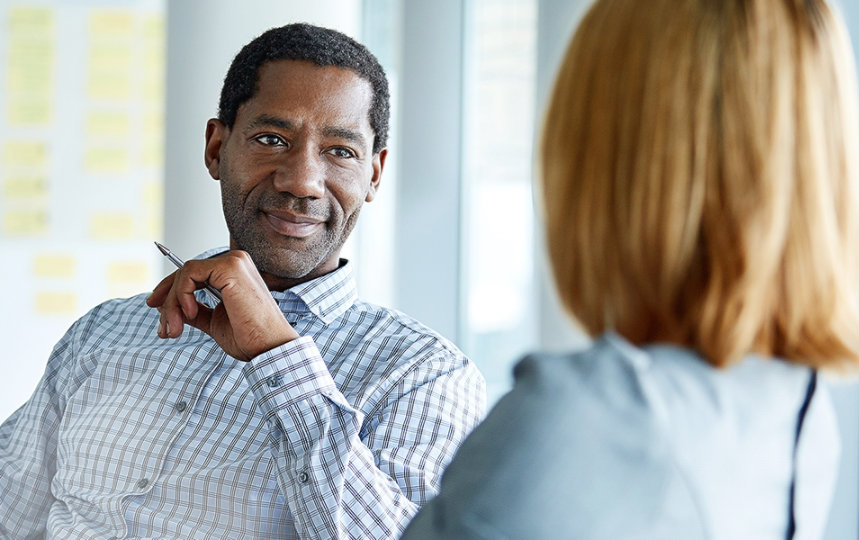 Two colleagues talking together while sitting in a modern office. 