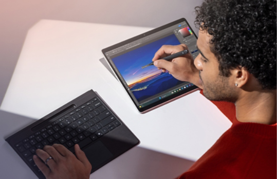 En person bruker frakoblet Surface Pro Flex Keyboard og Slim Pen til å redigere et bilde på deres Surface Pro.