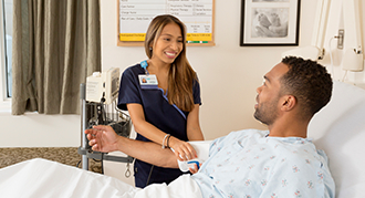 Female nurse caring for female patient at bedside