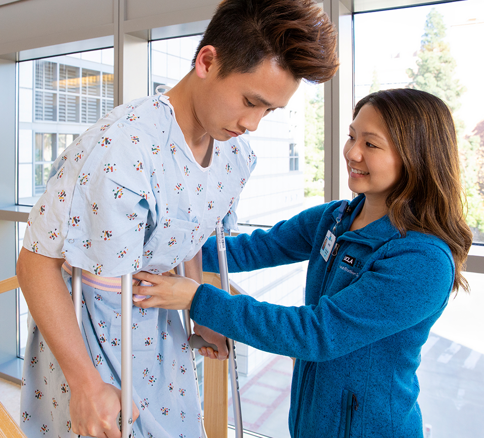 Female physical therapist helping male patient on crutches