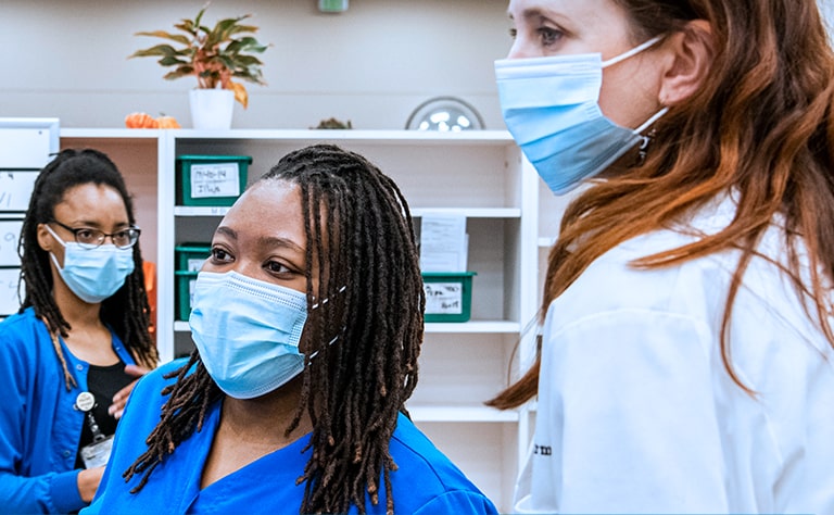 3 women medical professionals around a hospital workstation