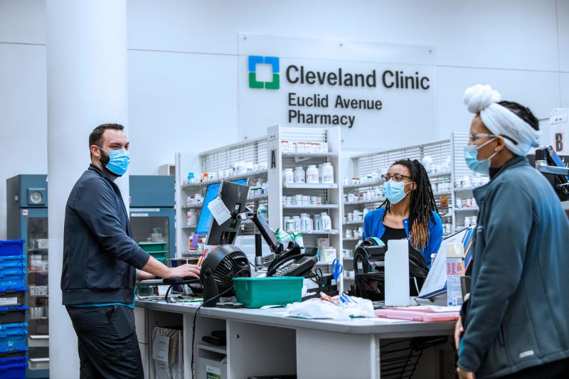 3 pharmacy professionals standing around a desk in the pharmacy