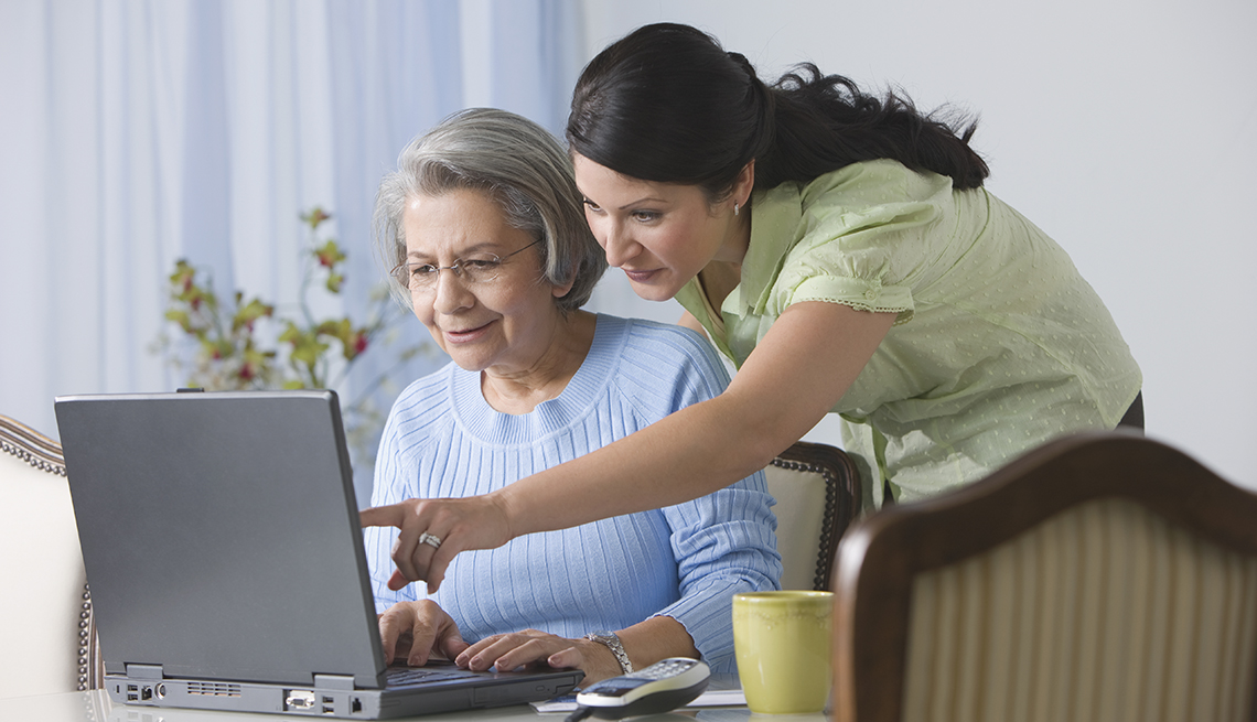 woman helping older woman with something on laptop