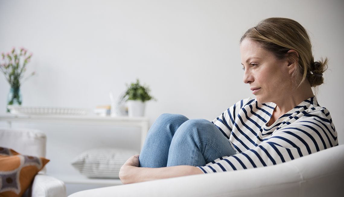 woman sitting in armchair holding legs