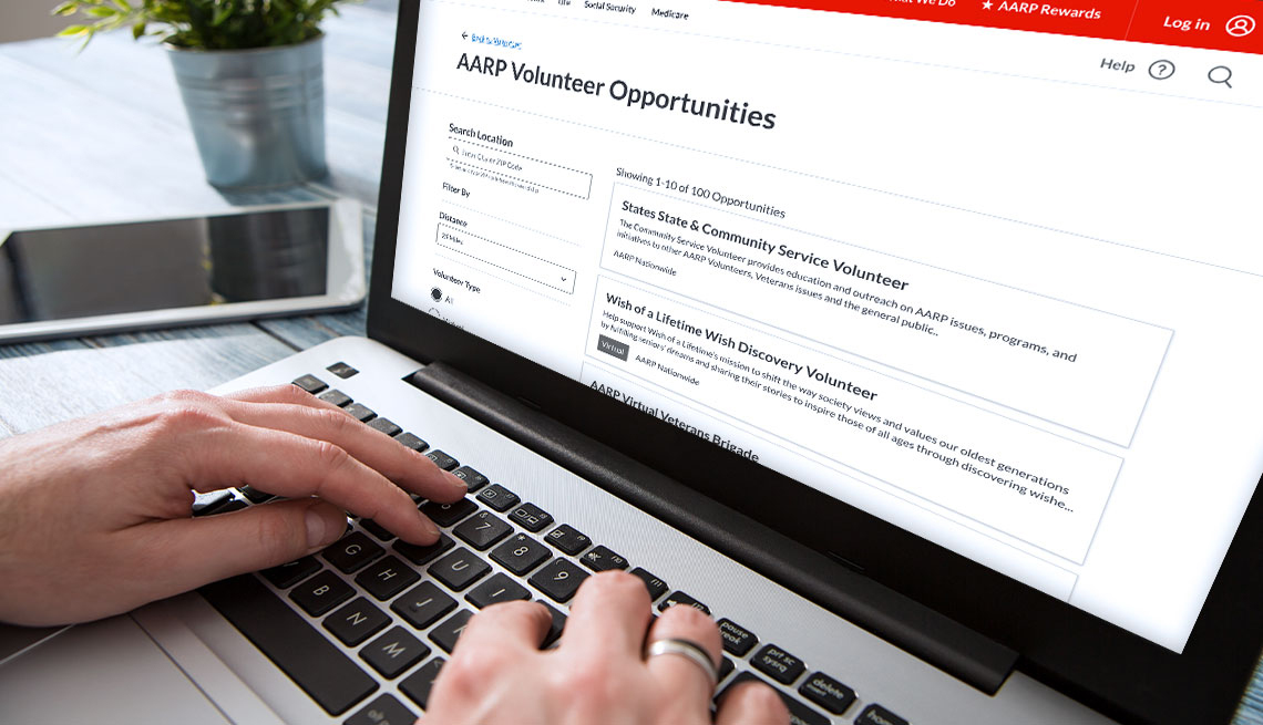 close up of a person looking up a a r p volunteer opportunities on a laptop computer