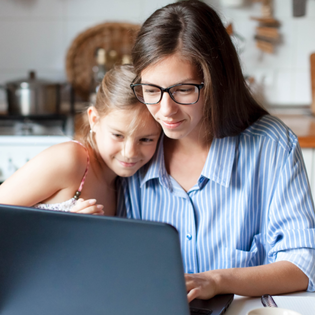 A mom and daughter use the computer together.