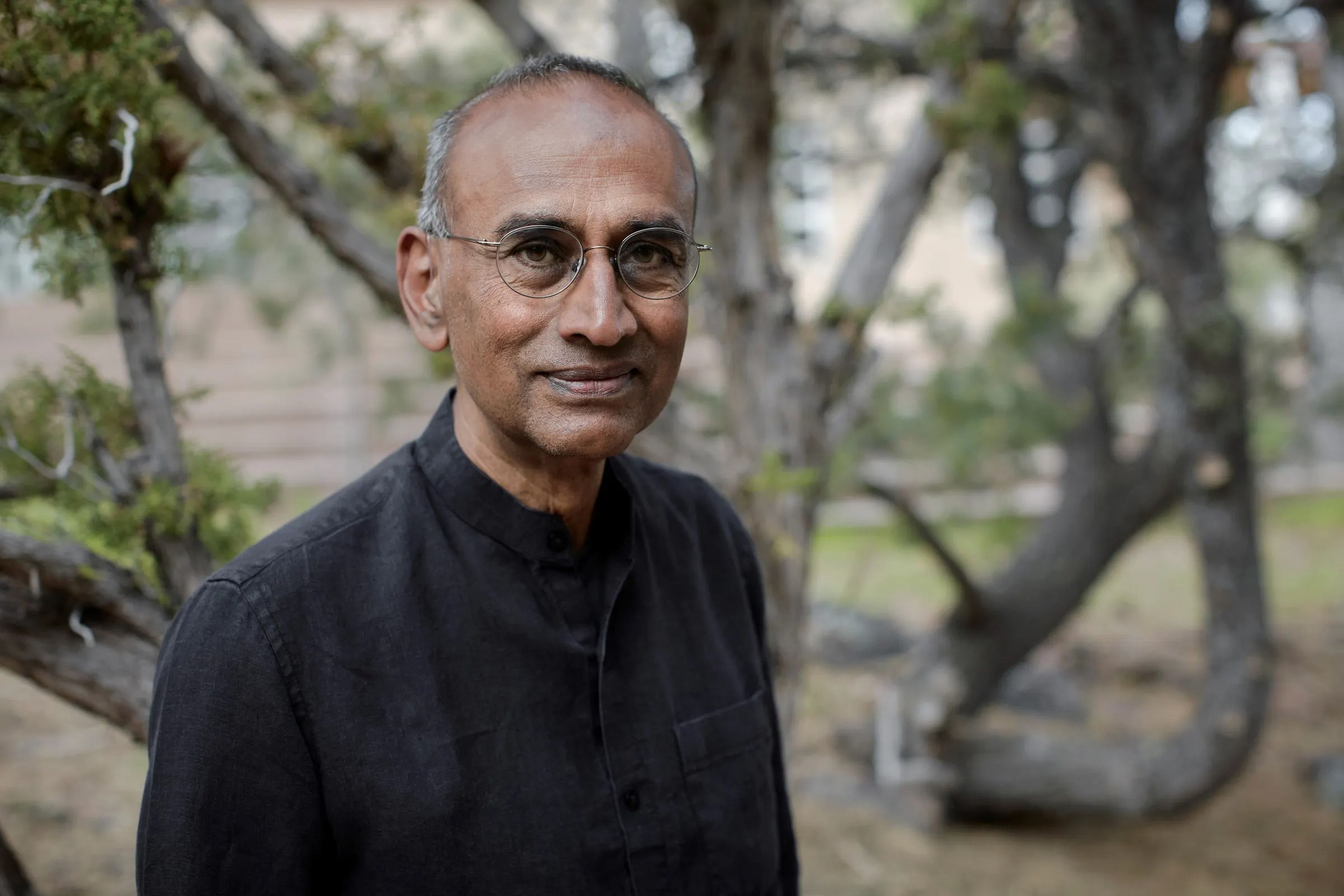 A headshot of Venki Ramakrishnan standing in front of a tree.