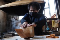 An artisan, Isao Takashimizu, wraps a wood piece around a cylindrical mold to form the side of a round container at Odate Kougeisha Co. Ltd. in Odate, Akita Prefecture, on Sept. 25, 2021. (Satoshi Takahashi) 