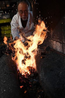 Swordsmith Yoshindo Yoshihara is seen heating "tamahagane" steel, as he operates a traditional bellows and sends air blasts to the forge, while charcoal burns, in Tokyo's Katsushika Ward on Feb. 14, 2022. By heating the tamahagane to a maximum of 1,300 degrees Celsius, impurities are burned. (Mainichi/Emi Naito)