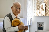 Takashi Morita is seen holding a beloved stuffed animal in Sao Paulo, Brazil, on April 17, 2023. "We hibakusha cannot remain silent," he said. A photograph of his wife Ayako, who passed away in 2009, is seen beside him. (Mainichi/Toshiyuki Sumi)