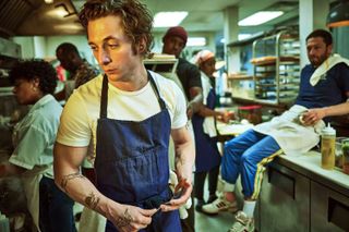 jeremy allen white as carmy wearing an apron in a kitchen in The bear