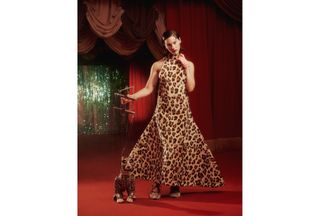 A photo of Gracie Abrams wearing a leopard print voluminous F/W 24 Marni dress with Rochas shoes and posing with a cheetah puppet for Who What Wear's fall issue cover story.