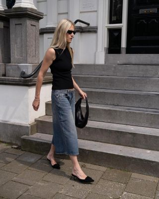 Woman wearing jeans and a black tank top.