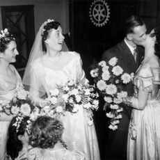 Groom kissing 1 bride while other brides look on