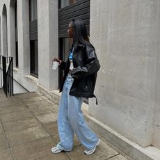 influencer wears white t-shirt with leather jacket, jeans and sneakers