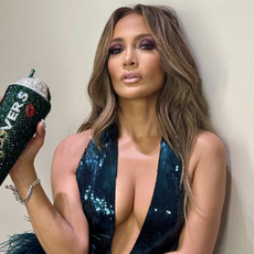 jennifer lopez wears a teal sequin gown with feathers and a matching rhinestone tumbler