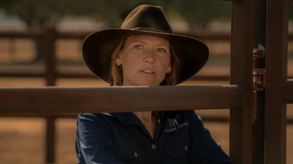 Anna Torv as Emily Lawson, standing behind a wooden fence, in &#039;Territory.&#039;