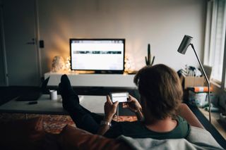 A man using his phone while watching TV