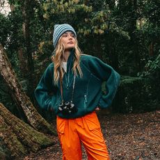 model. wears green fleece orange pants and a hat